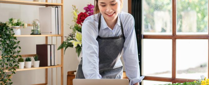 florist-in-apron-using-laptop-to-working